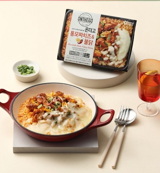 Repas complet avec viande, légumes et riz, couverts et verre sur une table avec fond beige.