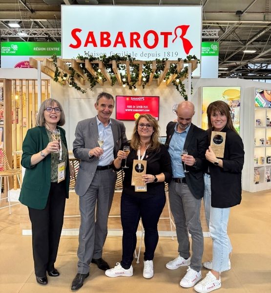 Photo de groupe avec des personnes debout sur le stand Sabarot, tenant des prix.