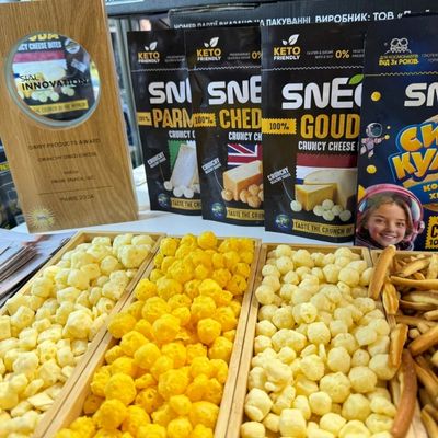Boules de fromage de couleur jaune et orange disposées sur une table avec un paquet de produit.
