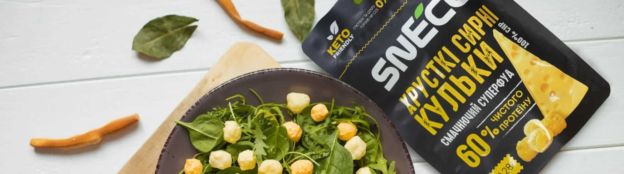 Emballage de produit avec des boules de fromage sur une salade verte.