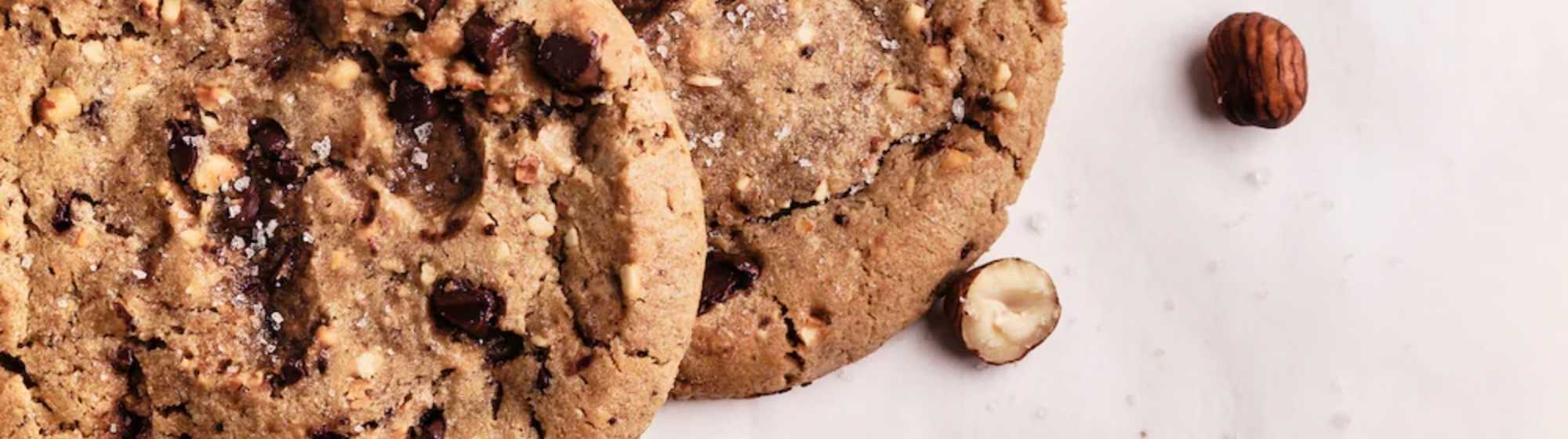 Gros plan sur des cookies aux pépites de chocolat et noisettes, saupoudrés de sel.