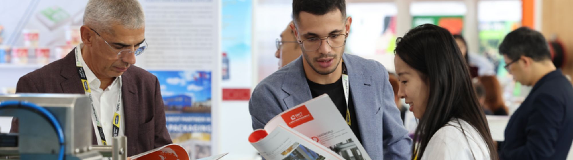 Visiteurs consultant des brochures produits et des solutions d’emballage sur un salon professionnel international