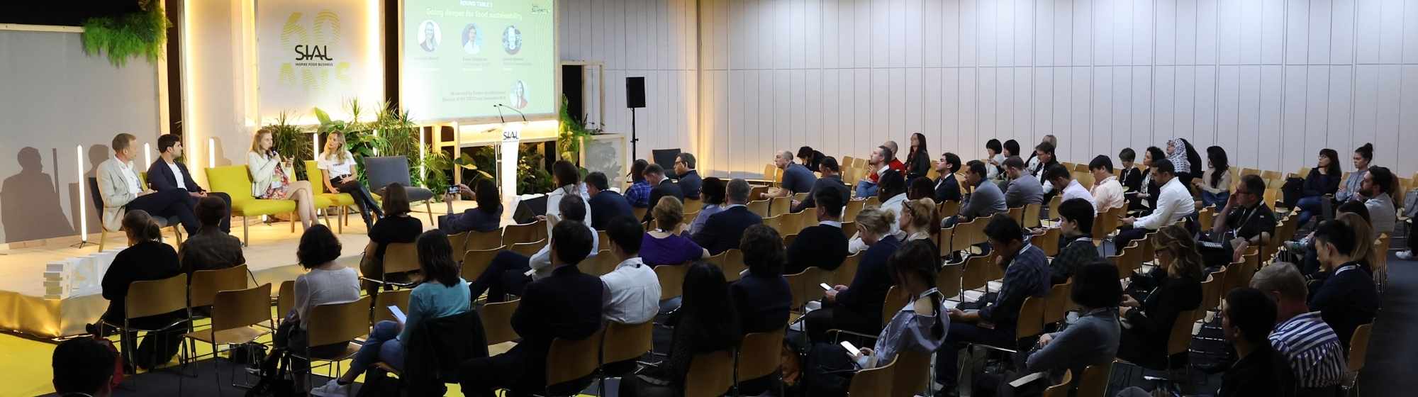 Table ronde SIAL avec intervenants sur scène et public assistant à une conférence professionnelle