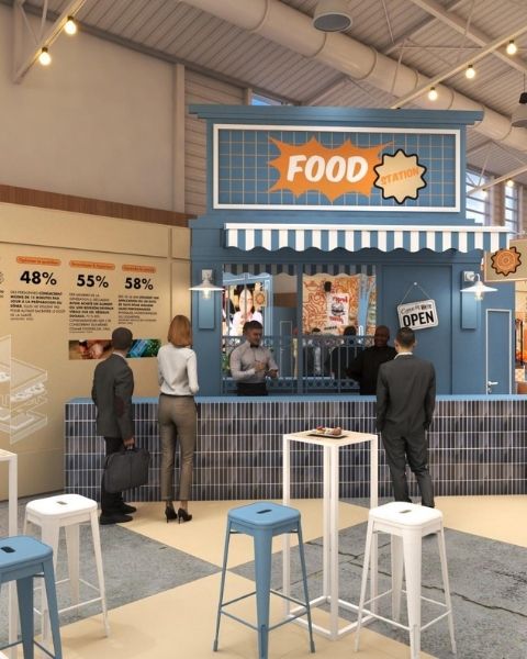 Stand Food Station bleu dans un espace événementiel, avec comptoir de service, tabourets et visiteurs en attente.