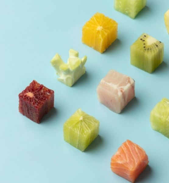 Cubes de fruits et de poisson disposés sur fond bleu, avec orange, kiwi, agrumes et saumon.