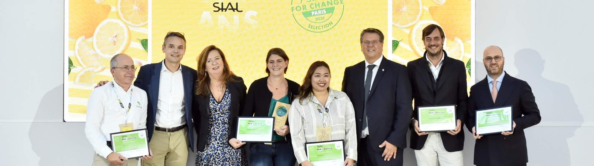SIAL For Change winners posing with certificates in front of a yellow screen at SIAL Paris.