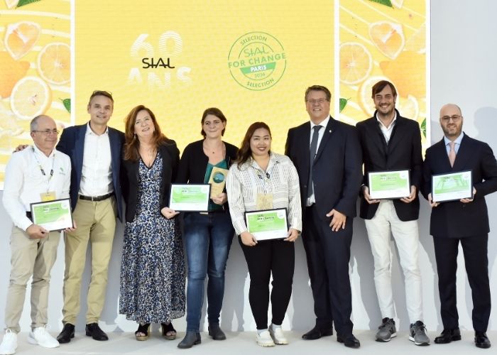 Groupe de lauréats posant avec certificats sur scène lors du SIAL for Change 2024 à Paris, devant un fond jaune