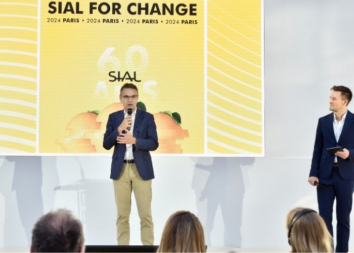Vue large d’une conférence SIAL Paris avec intervenant sur scène et public assis sous une verrière lumineuse