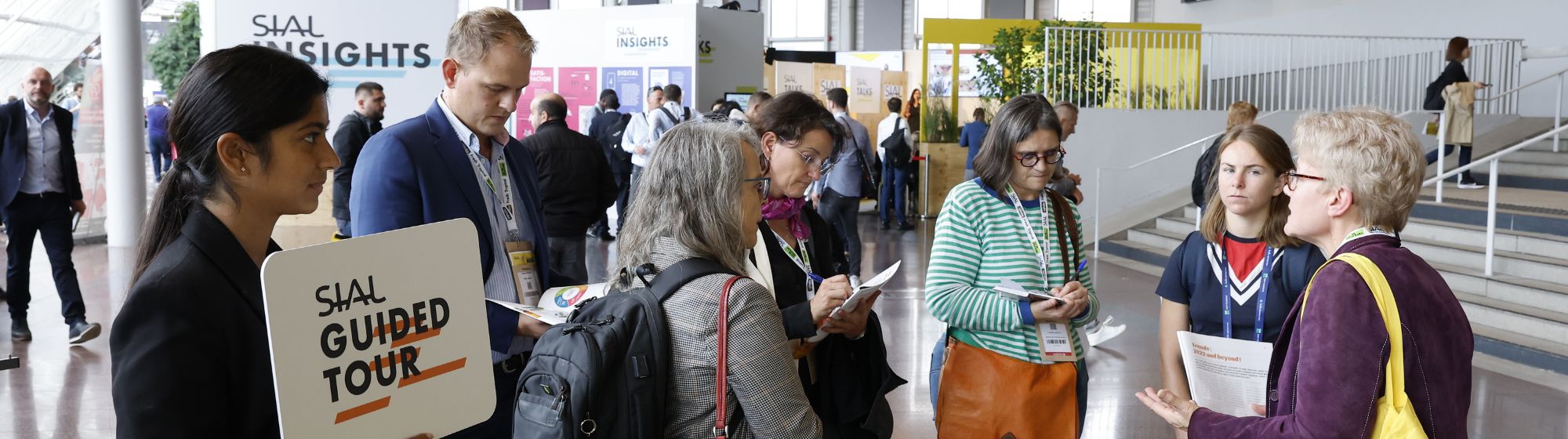 Groupe de participants à SIAL écoutant un guide pendant une visite guidée avec un panneau 'SIAL Guided Tour'