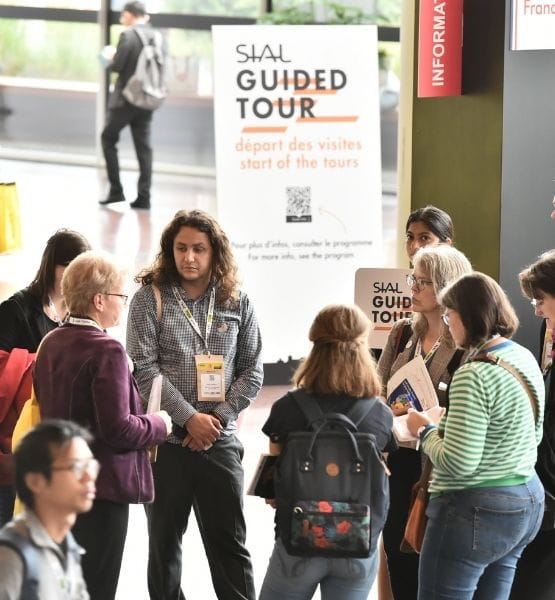 Group of visitors attending a guided tour at the SIAL exhibition, gathered near the starting point with a "SIAL Guided Tour" sign in the background.