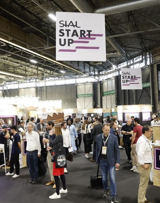 Aisle at the SIAL exhibition in the Startup section with several visitors interacting around booths dedicated to innovative startups.