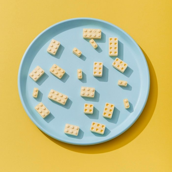 Brick-shaped food pieces on a blue plate over yellow background