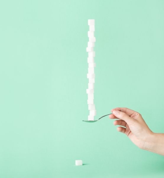 Sugar cubes stacked on a spoon against green background