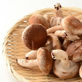Fresh button mushrooms arranged in a wicker basket on a light background.
