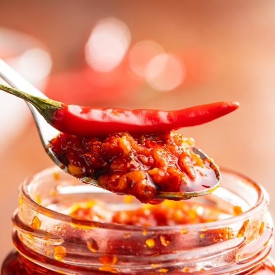 Cuillère avec pâte de piment rouge dans un pot