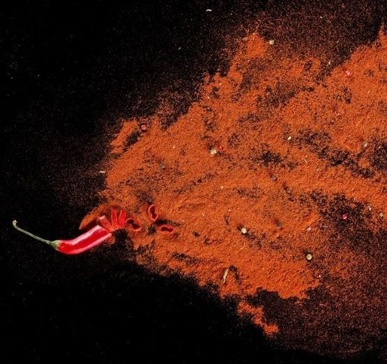 Piment rouge épicé et poudre de piment sur un fond noir.