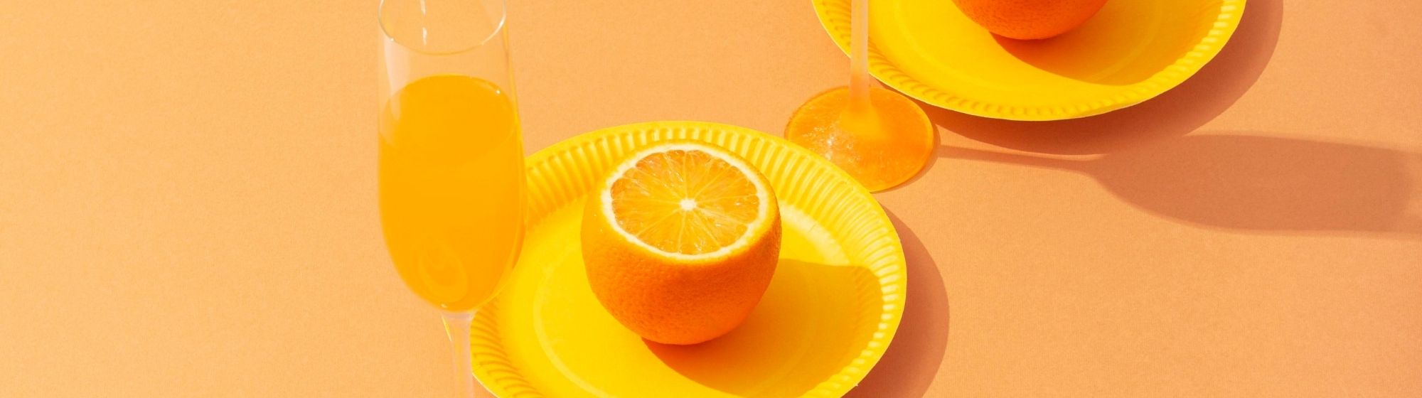 Flûtes de champagne orange avec agrumes sur fond minimaliste lumineux