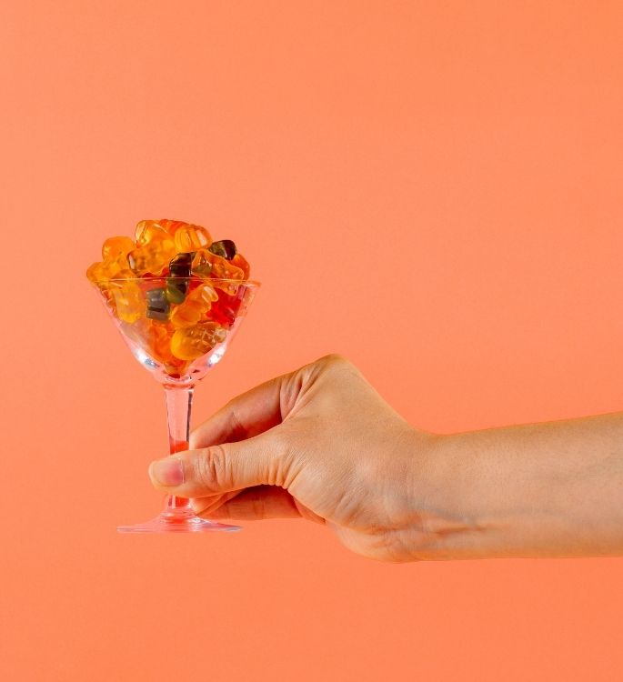 Verre à pied en forme de tulipe garni de bonbons sur fond orange
