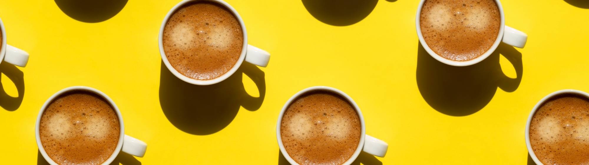Coffee cups composition on yellow background