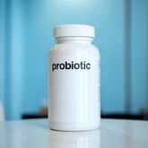 Probiotic bottle on a blue background, close-up view.