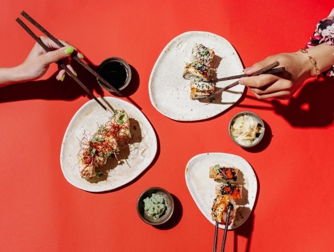Sushi plates with chopsticks on a red background, dynamic shot.