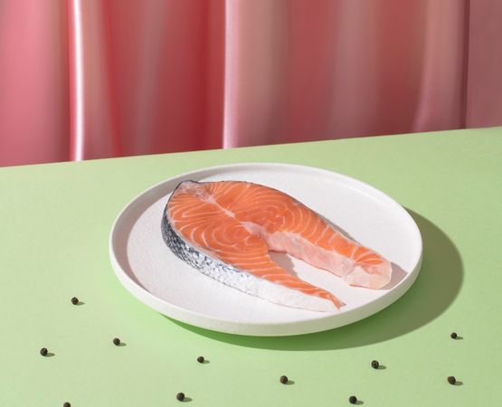 Pavé de saumon cru présenté sur assiette avec fond coloré, source naturelle de protéines et oméga 3Pavé de saumon cru présenté sur assiette avec fond coloré, source naturelle de protéines et oméga 3