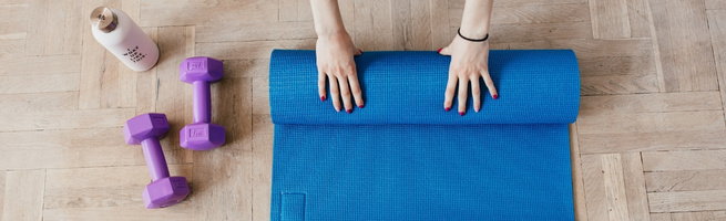 Hands rolling out a yoga mat