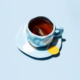 Cup of tea on blue background with lemon slice