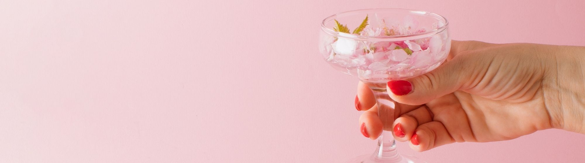 Verre de boisson fonctionnelle rose avec main sur fond neutre pastel