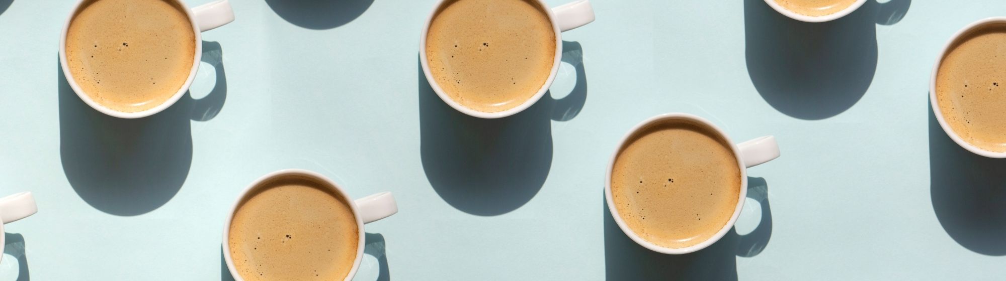 Top view of coffee cups with strong shadows on a light blue background