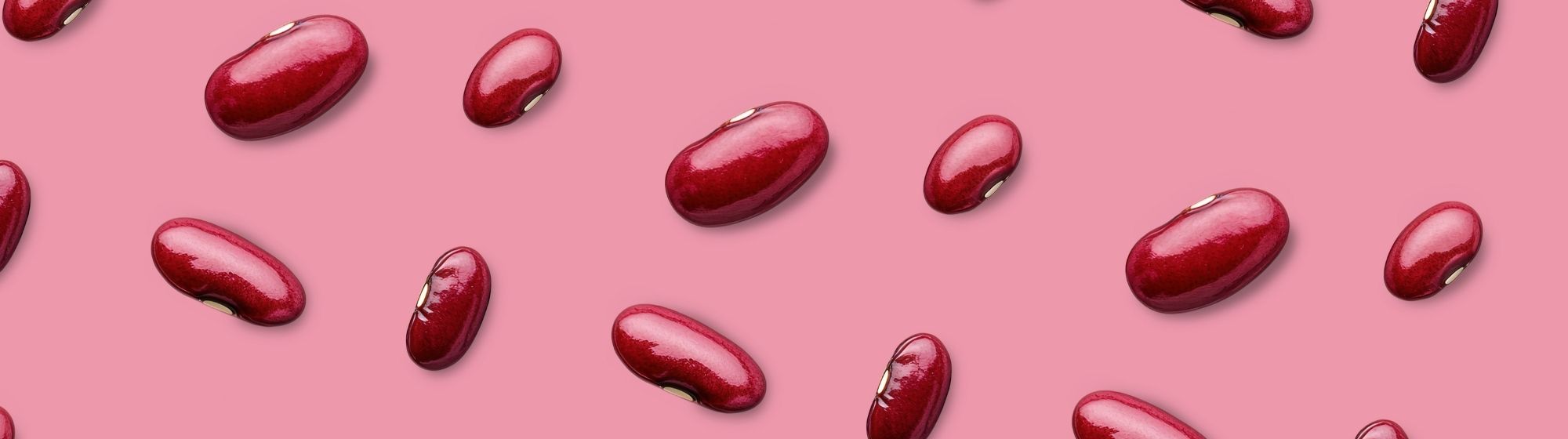 Banner with glossy red kidney beans spread across a plain pink background.