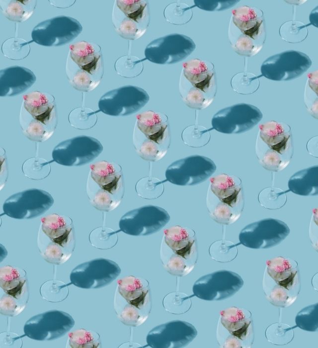 Glasses arranged in a repeating pattern on a blue background, top view.