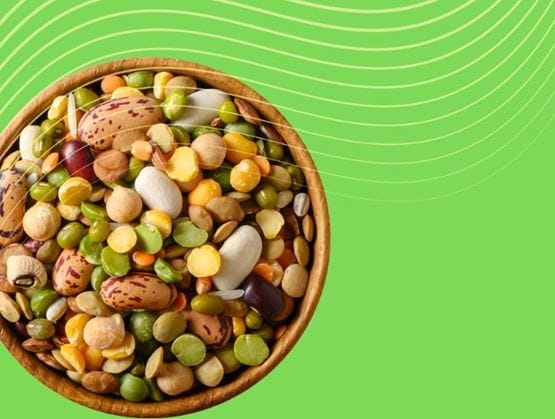 Bowl filled with various legumes (lentils, peas, beans) on a green background with wavy lines.