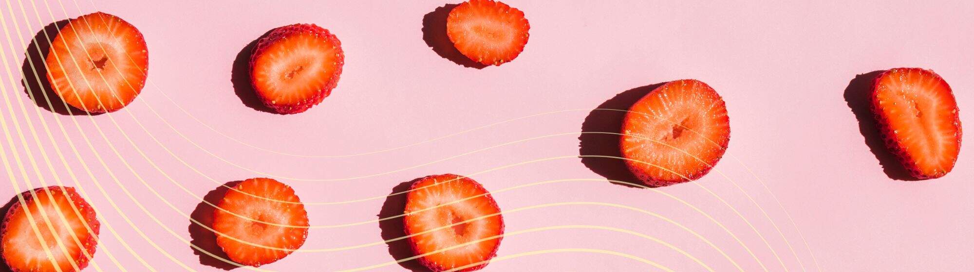 Slices of strawberries scattered on a light pink background with yellow wavy lines.