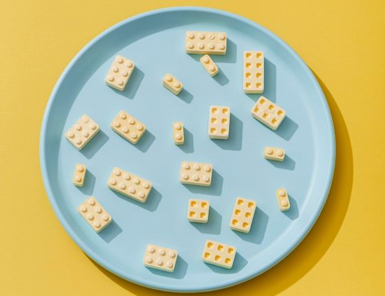 Assiette bleue sur fond jaune avec des blocs de construction en 3D, symbolisant l'innovation ouverte dans l'industrie alimentaire.
