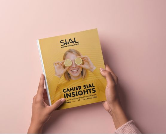 Two hands hold the yellow SIAL Insights booklet, with a cover showing a smiling person holding lemon slices.