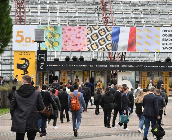 Entrée de SIAL Paris avec une foule marchant sous un grand panneau affichant les halles et des produits alimentaires